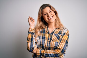 Fototapeta premium Young beautiful blonde woman wearing casual shirt standing over isolated white background with a big smile on face, pointing with hand and finger to the side looking at the camera.