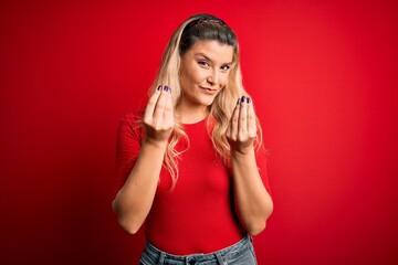 Fototapeta premium Young beautiful blonde woman wearing casual t-shirt standing over isolated red background doing money gesture with hands, asking for salary payment, millionaire business