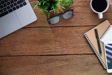 Wood office desk table with laptop, notebook and coffee cup with equipment other office supplies.