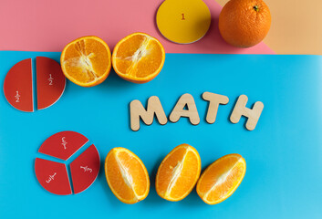 Close up mathematical fractions and oranges as a sample of parts on blue background. Creative, fun...