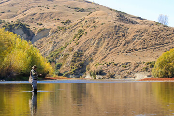 Fly fishing man on a river in Hawkes Bay New Zealand in Autumn