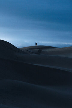 People standing on sand dune during sunrise