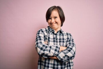 Young down syndrome woman wearing casual shirt over pink background happy face smiling with crossed arms looking at the camera. Positive person.