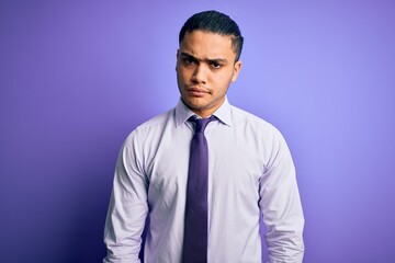 Young brazilian businessman wearing elegant tie standing over isolated purple background skeptic and nervous, frowning upset because of problem. Negative person.