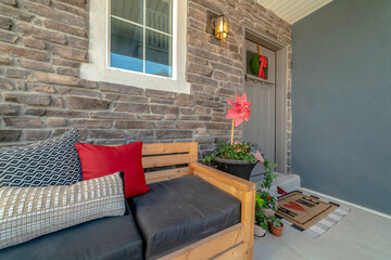 Wooden bench with pillows at the porch of home with glass paned gray front door