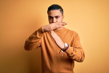 Young brazilian man wearing casual sweater standing over isolated yellow background Doing time out...