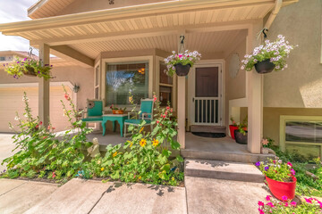 Home exterior with bay window on front porch decorated with flowers and plants
