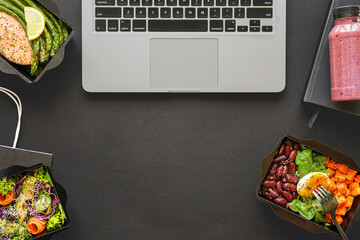 Office food delivery takeout lunch boxes containers delivered in office on black table workplace. Ready take away snack daily healthy meal dinner at work desk flat lay desktop top view, copy space.