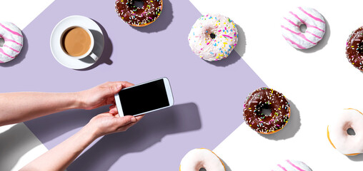 Person using a smartphone with donuts from above