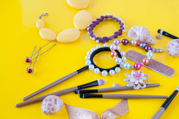 Hair bands, beads, cosmetic brushes and hair clips on a yellow background