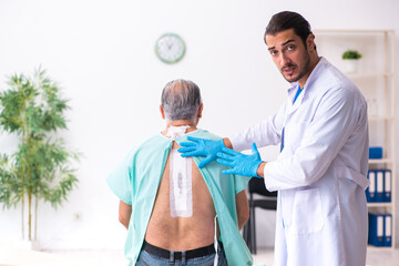 Fototapeta premium Old man visiting young male doctor