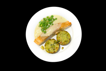 Top view of grill salmon, potato, and fresh Peas with cream sauce on white plate.