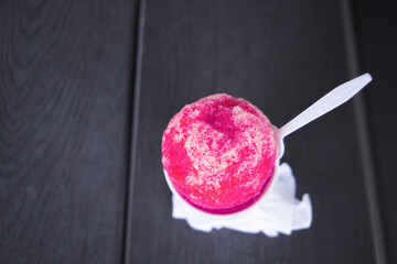 A vibrant hot pink snowball or snocone shaved ice summer treat or dessert
