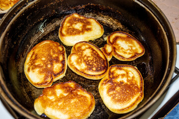 delicious fritters fried in a black pan exuding the aroma of fresh pastries