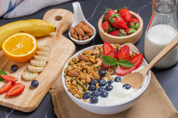 Bowl of homemade granola yogurt with fresh berries on breakfast table milk and mixed fruit.