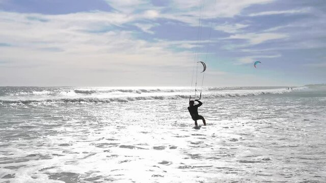 A kitesurfer spins his board during a tack then heads out to sea