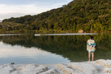 Fototapeta premium Mulher pescando tranquilamente no Rio Guaratuba, litoral Norte de São Paulo