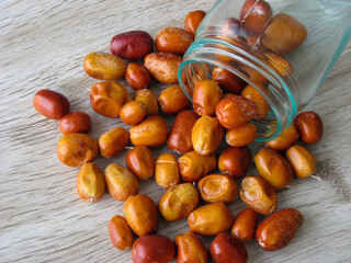 Organic dried fruit of Oleaster scattered from a glass bottle on wooden table. Fresh fruit of the Oleaster, Silver berry,Persian olive,   or wild olive or russian olive close up. Background.  ..