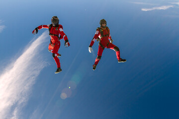 Two sports parachutist build a figure in free fall. Extreme sport concept. - obrazy, fototapety, plakaty