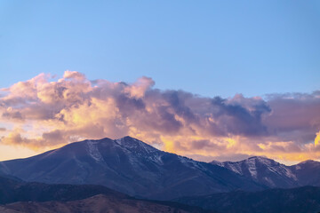 Naklejka na ściany i meble Clouds gathering over the mountain at sunset