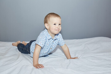 Fototapeta premium Kid playfully smiles while lying on a white blanket