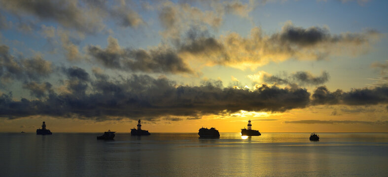 Beautiful sunrise from the coast with awesome sky of scattered clouds and ships in the bay with calm sea