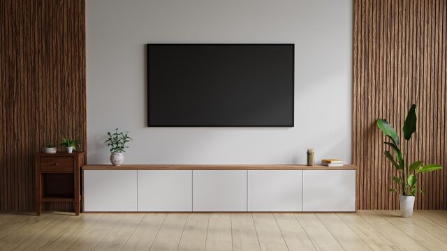 Large TV on the wall. The white room on the side decorated with wood, with trees and books on the table.3D Rendering.