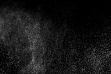 Abstract splashes of water on black background. Freeze motion of white particles. Rain, snow overlay texture.