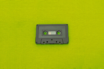 Fototapeta premium Top View of an old black cassette over a green cloth. Fashion and retro music concept