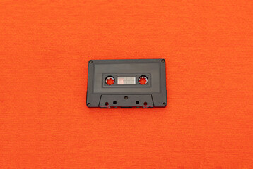 Top View of an old black cassette over a orange cloth. Fashion and retro music concept