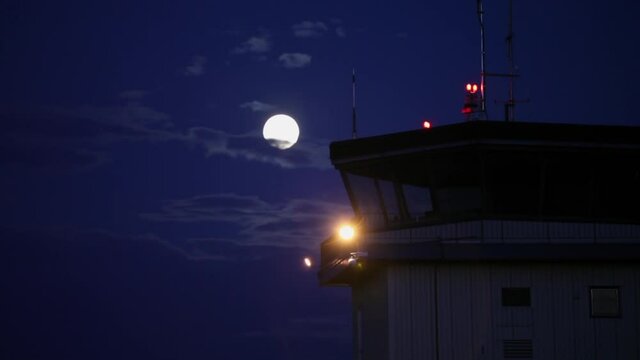 Time lapse of full moon in clouds. Airport control tower.