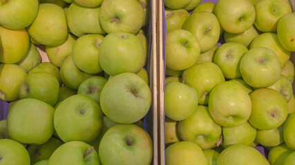 Juicy, round, hard apples with glistening green skins lay in heaps in wooden crates that were for sale. Concept: healthy, organic, nutritious food for life.