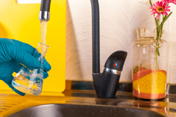 water purification specialist tap water pours into a glass flask.