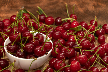 Red berries of a cherry in a white ceramic bowl. On a wooden background. A lot of berries. Summer.