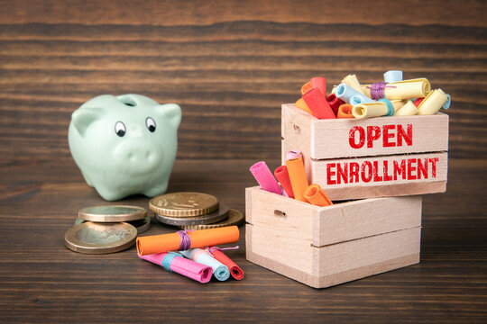 Open Enrollment concept. Colored papr scrolls in wooden boxes on dark wooden background