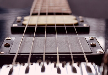 closeup to a six black electric guitar strings and microphones . Instruments and music concept