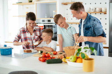 Mother and father making breakfast with sons. Young family preparing delicious food in kitchen.
