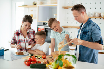 Mother and father making breakfast with sons. Young family preparing delicious food in kitchen.