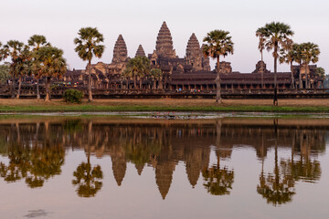 Fototapeta na wymiar Cambodia; Feb 2020: Facade of Angkor wat temple reflected on the water at sunset time, pink atmosphere. The largest religious monument in the world. Angkor wat, Siem Reap, Cambodia