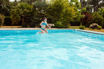 cute little girl jumping in the pool