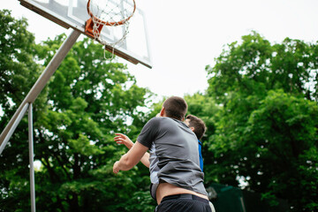 Two young men playing basketball in the park. Friends having a friendly match outdoors