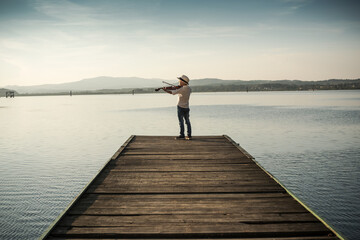 Fototapeta na wymiar boy plays the violin on the lake