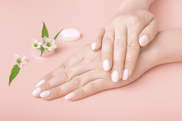 Hands of a beautiful woman on a peach pink background. Delicate hand s with natural manicure, clean skin. white nails.