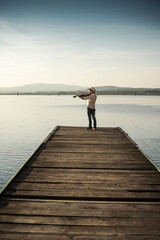 boy plays the violin on the lake