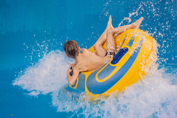 Boy on a pool float on artificial waves in a water park