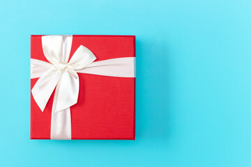 Red gift wrapping with white bow, on the blue background