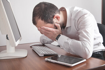 Caucasian stressed businessman sitting in office.