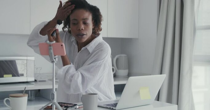 medium shot of an african woman recording beauty makeup tutorial at home a beauty influencer sharing the processing of using makeup brush chating with netizen living broadcast at hotel