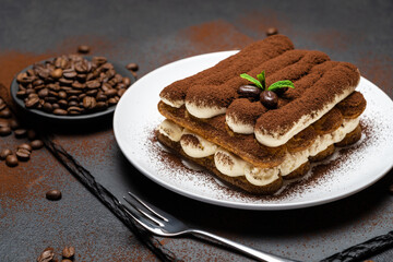 Classic tiramisu dessert on ceramic plate on concrete background