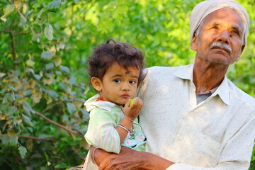 A Asian child and grandfather standing in the garden